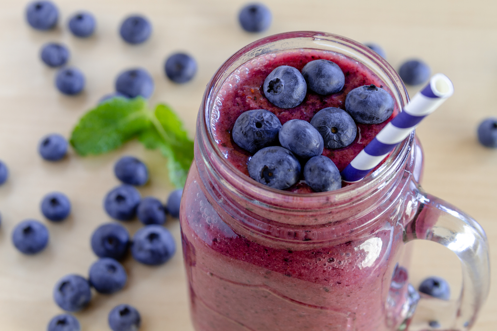 mason jar filled with fresh fruit smoothie and blueberries